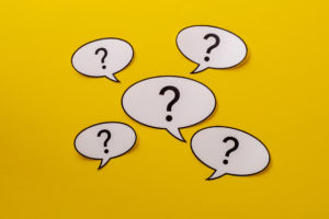 Five speech bubbles with question marks centered over a bright yellow background
