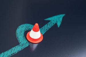 A chalk drawing of an arrow diverting around a traffic pylon