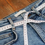Measuring tape and jeans on a wooden background