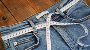 Measuring tape and jeans on a wooden background