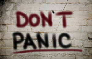 A brick wall with the words "Don't Panic" spray painted on it.