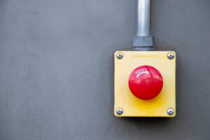 A large, red, mechanical button labeled reset, mounted on a wall.