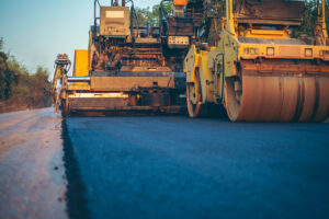 Construction equipment being used to repair an asphalt road.