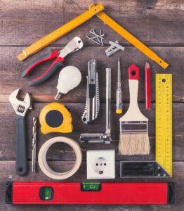 Tools arranged in the shape of a house on a wooden background