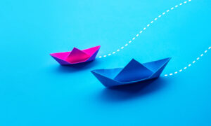 Two folded paper boats plotting a course together