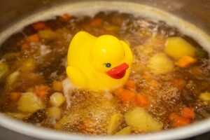 Yellow rubber duck swimming in a boing pot of soup