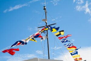 A ship's mast with signal flags against blue sky