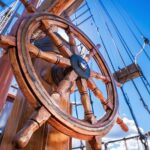 A wooden steering wheel on the deck of a sailing ship